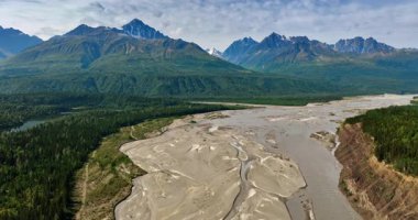 Alaska 'nın vahşi doğasının ikonik görüntüsü, ABD. Nehrin yukarısındaki drone görüntüleri yemyeşil orman ve dağların arasında akıyor..
