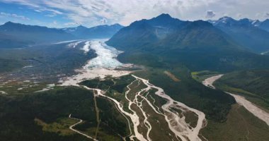Dağlardaki güneşli vadi, dallanan nehirle kesişiyor. Alaska, ABD 'nin güzel doğa manzarasına hava perspektifi.