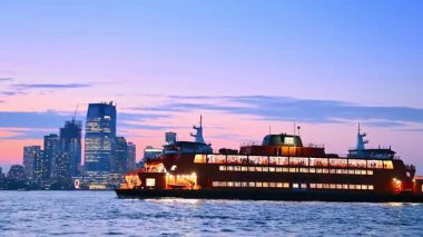 Nehir manzarası boyunca hareket eden uzun ve modern bir tekne. Günbatımında New York 'ta nehir gezisi.