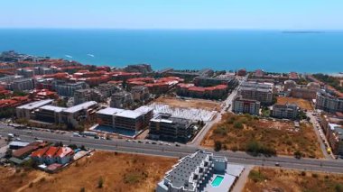 Kentsel mimarisi olan modern bir kıyı şehrinin havadan görünüşü. Modern bir sahil şehrinin insansız hava aracı görüntüleri konut binalarını ve deniz ufkunu gösteriyor..
