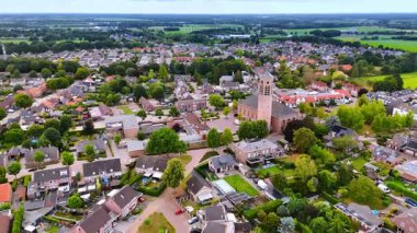 Kilise kulesi olan Hollanda köyünün insansız hava aracı görüntüsü. Merkezi bir kilise kulesi, ev ve yeşillik karışımı bir Hollanda köyü..