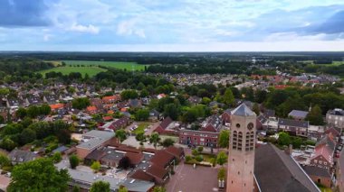 Kilise kulesi olan bir Hollanda kasabasının havadan görünüşü. Tarihi kilise kulesi ve çevreleyen yeşil tarlaları olan küçük bir Hollanda kasabasının panoramik drone görüntüsü.