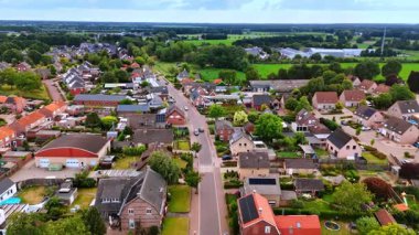 Hollanda 'da evleri ve yeşil tarlaları olan bir yerleşim yeri manzarası. Hollanda 'da bir yerleşim sokağının insansız hava aracı görüntüsü, evleri, bahçeleri ve çevreleyen yeşil alanları gösteriyor..