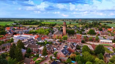 Kilise kulesi ve çevre evleri olan Hollanda kasabasının insansız hava aracı görüntüsü. Önde gelen bir kilise kulesi ve çevresindeki evleri ve tarlaları olan bir Hollanda kasabasının insansız hava aracı görüntüsü..