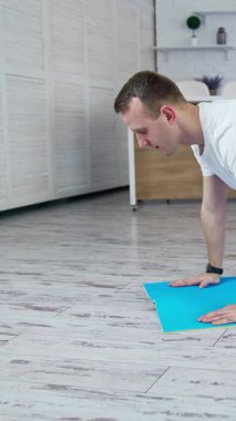 Sağlıklı ve güçlü bir adam evde çalışıyor. İçerideki adam karantinada egzersiz yapıyor. Dikey video