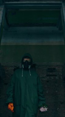 Yok edilmiş şehirde koruyucu giysili bir adam. Kıyamet Şehri 'nde yaşayan biri. Dikey video