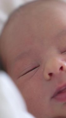 Küçük, şirin, yeni doğmuş bir bebeği kapat. Yeni doğmuş küçük bebek uyuyor. Dikey video