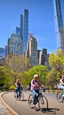 New York, USA, 1 August 2025: Cyclists riding in Central Park with skyscrapers in the background.