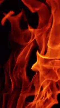 Siyah arka planda yangın. Karanlıkta hareket eden sıcak kırmızı alevler. Kapatın. Dikey video