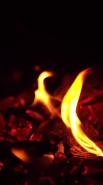 Charcoals with little flame burning on. the embers are moved and tiny sparks fly up. Close up. Black backdrop. Vertical video