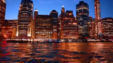 Brilliant illumination of night New York reflecting in the East River waterscape. Watching the skyline of metropolis from the boat.