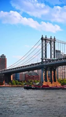 Long loaded barge moves under the Manhattan Bridge. Business logistics in New York, USA. Vertical video.