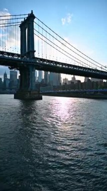 Approaching the Manhattan Bridge by the riverscape. Traffic jam on the highway at the waterfront of New York, USA. Vertical video.
