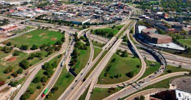 Fast cars and lorries move by the roads and freeways at daytime. Aerial perspective on the traffic system of Detroit, Michigan, USA.