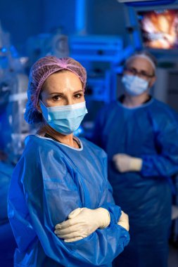 Robot cerrahi operasyonunda cerrahlar. Mavi önlüklü ve maskeli cerrahlar modern ameliyathanede robotik destekli ameliyat yapıyorlar..