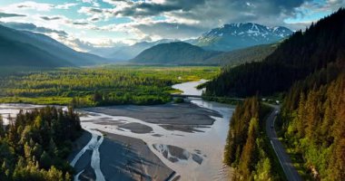 Flight over the branching river flowing at the mountain foot. Stunning scenery of Alaska, USA.