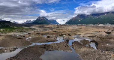 Rugged brown landscape with water from melting ice. Drone footage over the valley in the mountains of Alaska, USA.