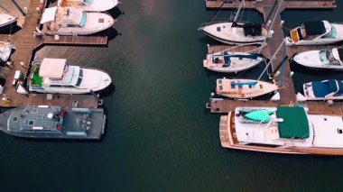 Footage over the wooden berths with numerous boats standing by. Approaching the waterfront with parking lot and green park in Jersey City, USA.