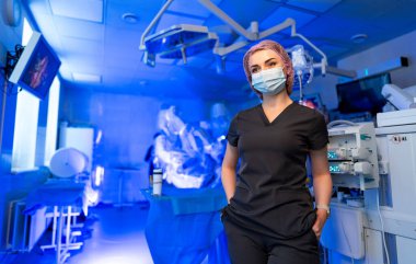 Ameliyathanede kendine güvenen bir hemşire var. Koruyucu maskeli hemşire ameliyathanede güvenle ayakta duruyor..