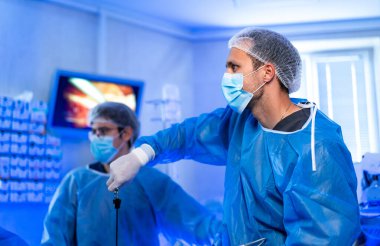 Laparoskopik ameliyat sırasında tıbbi ekip. Koruyucu giysiler ve maskeli doktorlar modern aletlerle laparoskopik ameliyat yapıyorlar..