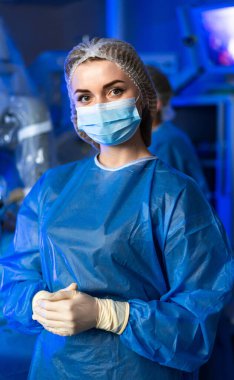 Ameliyathanede kadın cerrah portresi. Ameliyattan önce koruyucu maskeli ve cüppeli doktor.
