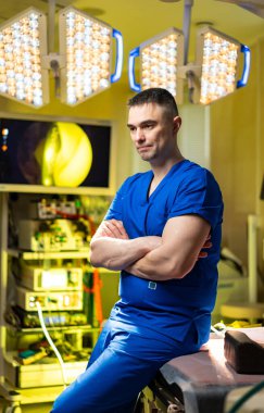 Cerrah ameliyattan sonra hastane katında oturuyor. Hastane koridorunda yerde oturan mavi önlüklü doktor yorgun görünüyor..