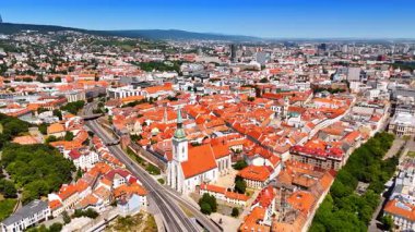 Slovakya 'nın Bratislava kentindeki eski kiliseye yaklaşıyoruz. Şehrin tarihi bölümündeki binaların turuncu çatılarının üzerindeki drone görüntüleri..