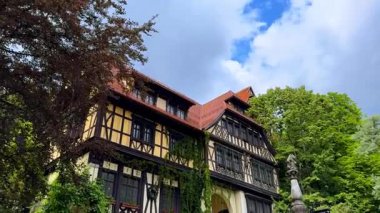 Yeşil sarmaşıkla kaplı eski moda bir bina. Yeşil ağaçlar yakınlarda yetişir. Romanya 'nın Prahova İlçesindeki Peles Kalesi.