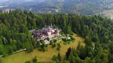 Dağın tepesindeki muhteşem şato yemyeşil çam ağacıyla çevrili. Romanya 'nın Prahova İlçesindeki Peles Kalesi' nin hava manzarası.