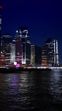 Geceleri ABD, New York 'u nehir manzarasından izliyorum. Işıltılı sahil şeridi boyunca East River 'da bir nehir gezisi. Dikey video.