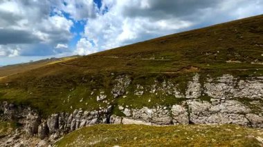Green hills and rocky cliffs of Bucegi Mountains. Panoramic view of green hills and rocky cliffs in Bucegi Mountains with dramatic clouds.