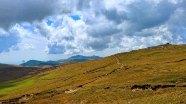 Scenic hiking path across Bucegi plateau. Long winding trail across plateau with cloudy sky in the Bucegi Mountains.