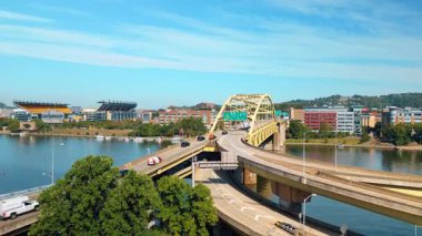 Flow of cars moving on the Fort Duquesne Bridge over the Allegheny River in Pittsburgh, Pennsylvania. Drone footage over the cityscape distancing from the bridge.