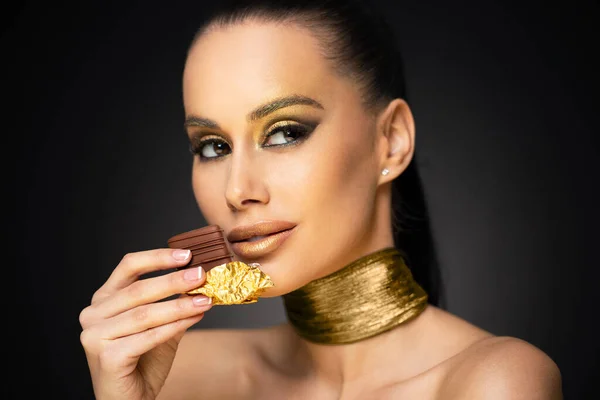 Piękne Zmysłowy Młody Brunetka Kobieta Jedzenie Czekolada Noszenie Złoty Makijaż — Zdjęcie stockowe