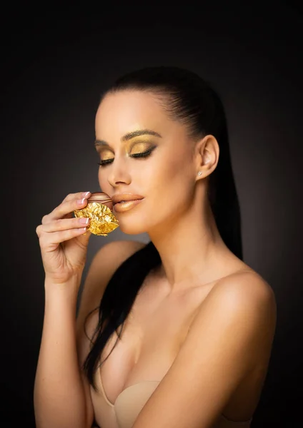 Όμορφη Αισθησιακή Νεαρή Μελαχρινή Μοντέλο Τρώει Σοκολάτα Φορώντας Χρυσό Μακιγιάζ — Φωτογραφία Αρχείου