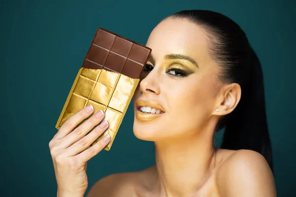 Όμορφη Αισθησιακή Νεαρή Μελαχρινή Γυναίκα Τρώει Σοκολάτα Φορώντας Χρυσό Μακιγιάζ — Φωτογραφία Αρχείου
