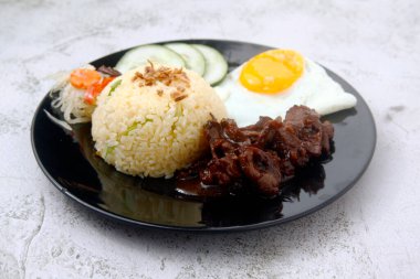 Photo of freshly cooked Filipino food called Tapsilog or thin beef slices, egg and fried rice.