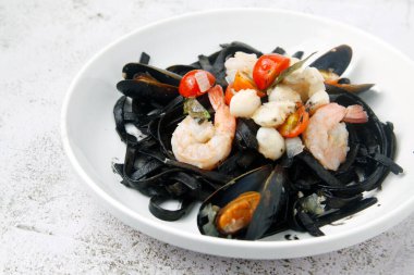 Çeşitli deniz ürünleri malzemeleriyle yeni pişirilmiş siyah makarna fotoğrafı..