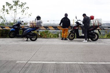 Angono, Rizal, Philippines - March 19, 2024: Motorcycle riders rest and stop at the side of the road. clipart