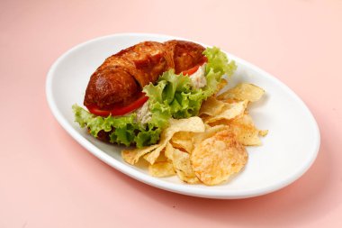 Photo of freshly made croissant with tuna spread filling served with chips. clipart