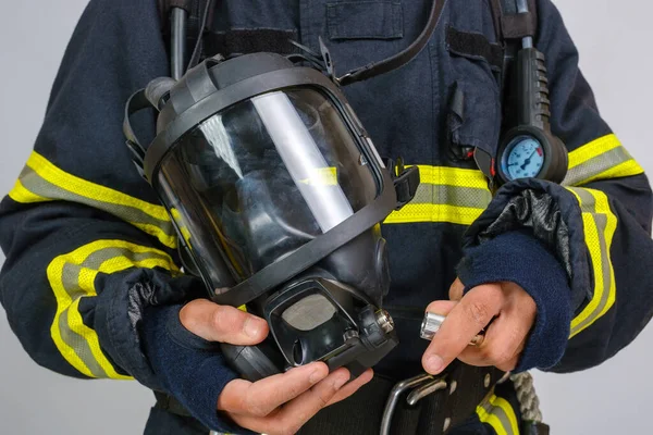 Full protective breathing air mask in hand of unrecognized african-american firefighter, rescue and fire fighter equipment