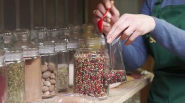 Satıcı kadın eli, satış rafının yanındaki plastik poşette kırmızı ve siyah biber karışımı bir şey koyar. Markette baharatlar