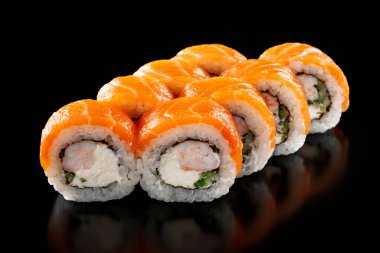 Karides, salatalık ve peynirli taze suşi ruloları siyah arka planda izole edilmiş.