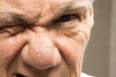 Close up of an older man with one eye closed squinting