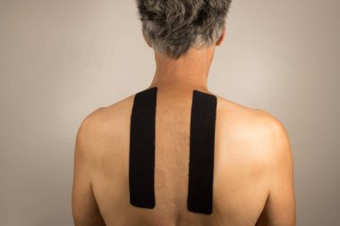 Mature Man with Kinesio Tape on his back for pain management