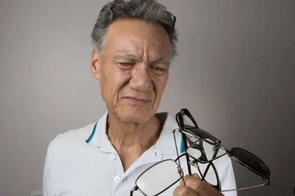 Mature Man Checking Out Holding All His Old Prescription Glasses — Stock Photo, Image