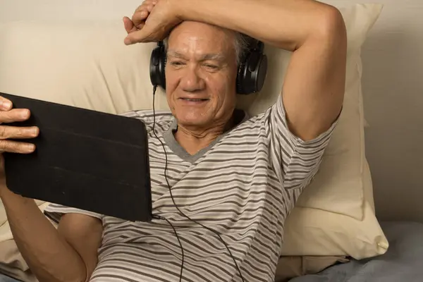 Mature Man Wearing Headphones Lying Bed Watching Movie His Ipad — Stock Photo, Image