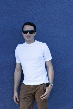 20 'li yaşlarda genç bir adam şehir merkezinde şık kıyafetler giyerek takılıyor. 