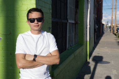 Yirmili yaşlarda genç bir adam şehir merkezinde şık kıyafetler giyerek takılıyor. 