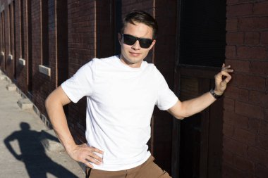 Yirmili yaşlarda genç bir adam şehir merkezinde şık kıyafetler giyerek takılıyor. 